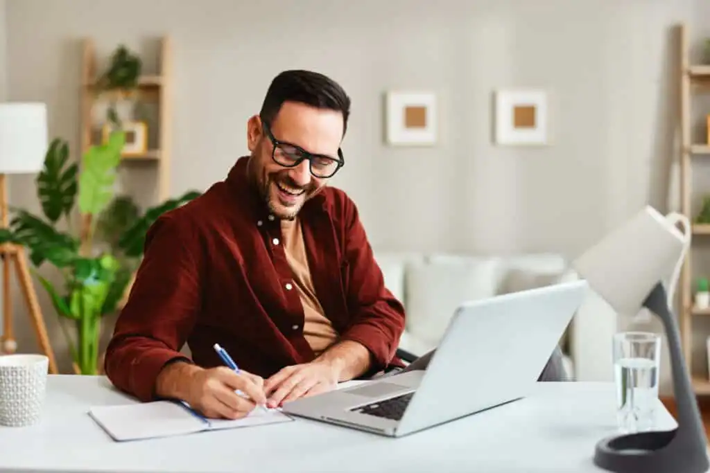 Young business man working at home with laptop and papers on desk - CORE CONNECT Young business man working at home with laptop and papers on desk