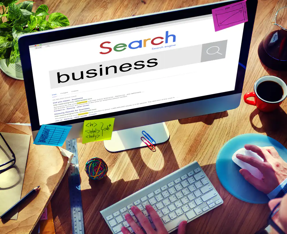 Desktop monitor shows a search results page with the large word 'business' on the screen