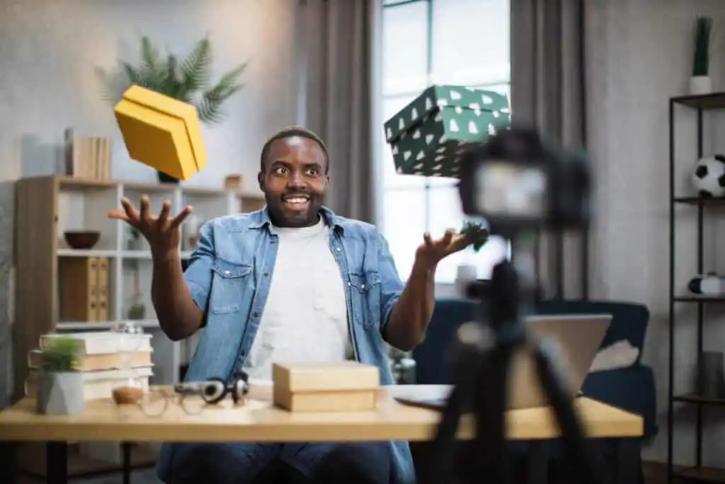 Man recording video blog while unpacking presents